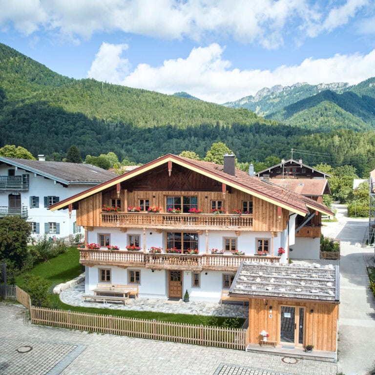 Oida Knoglerhof in Luftaufnahme – man sieht den ganzen alten Hof mit Berpanorama im Hintergrund.